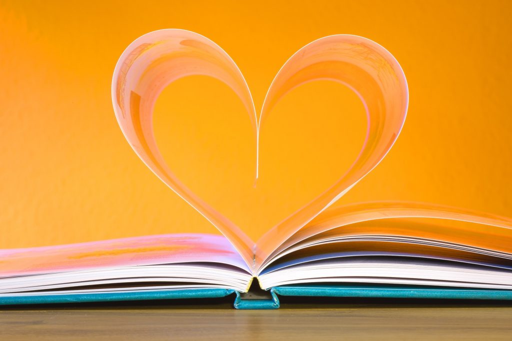 book on orange background with pages bent into a heart shape